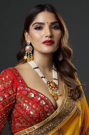 Woman wearing a red and yellow traditional outfit with jewelry on a dark background